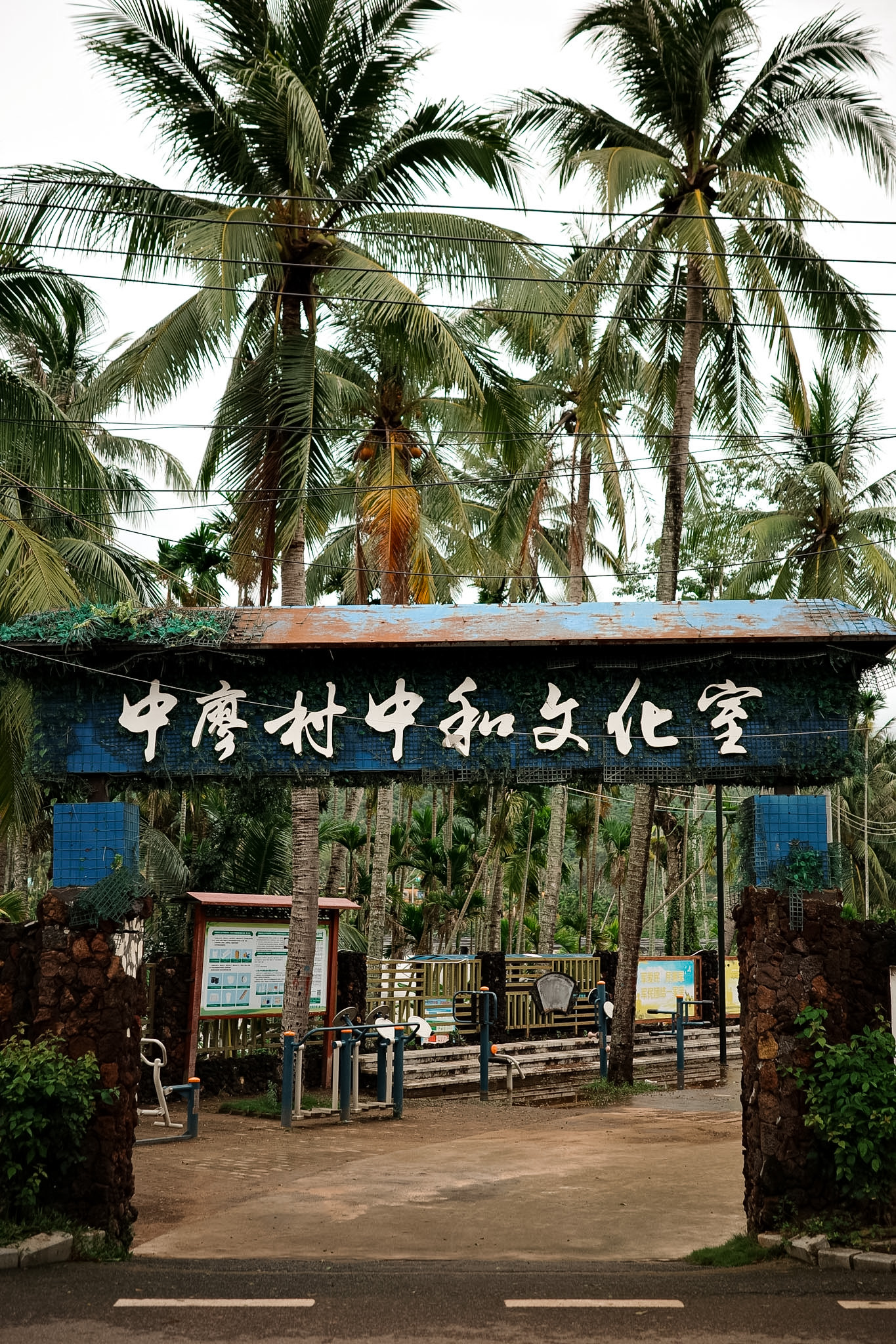 The gate of the Zhongliao village cultural center, its blue sign rusting under coconut palms, with no one inside.